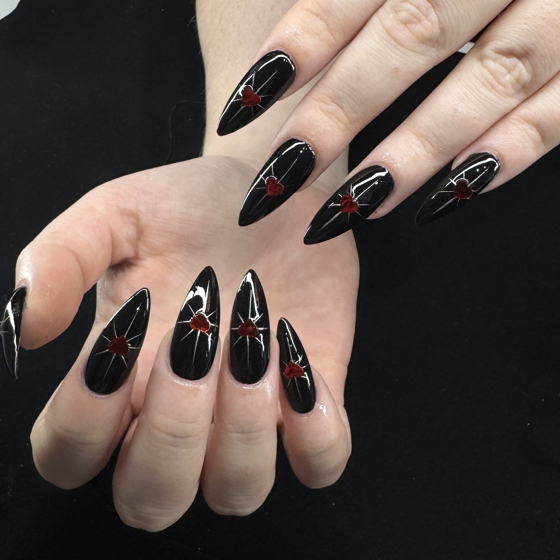 Glossy black stiletto nails with heart details